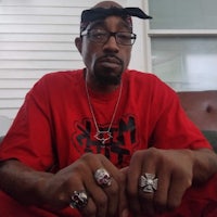 a man in a red shirt with a bandana on his head